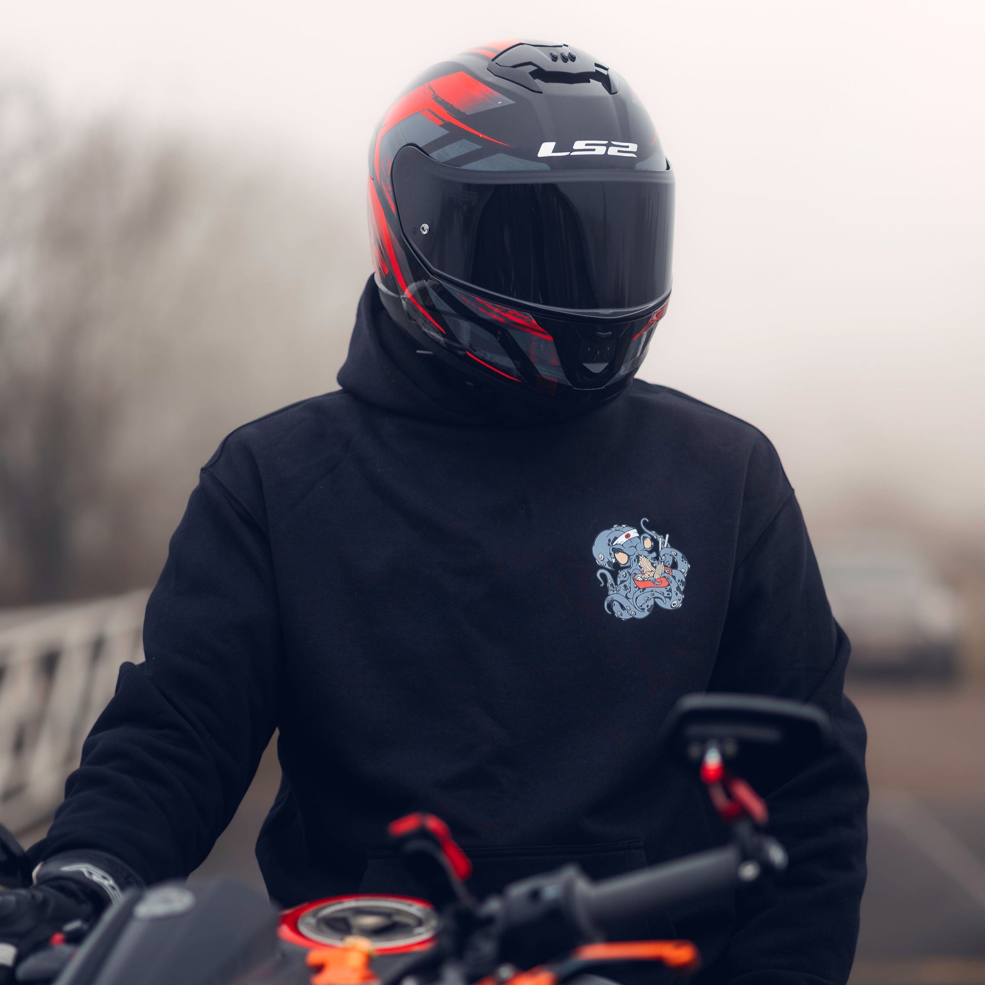 Throttle and Tarmac Black Oversized Octopus Hoodie being shown from the front and worn on a motorcycle.