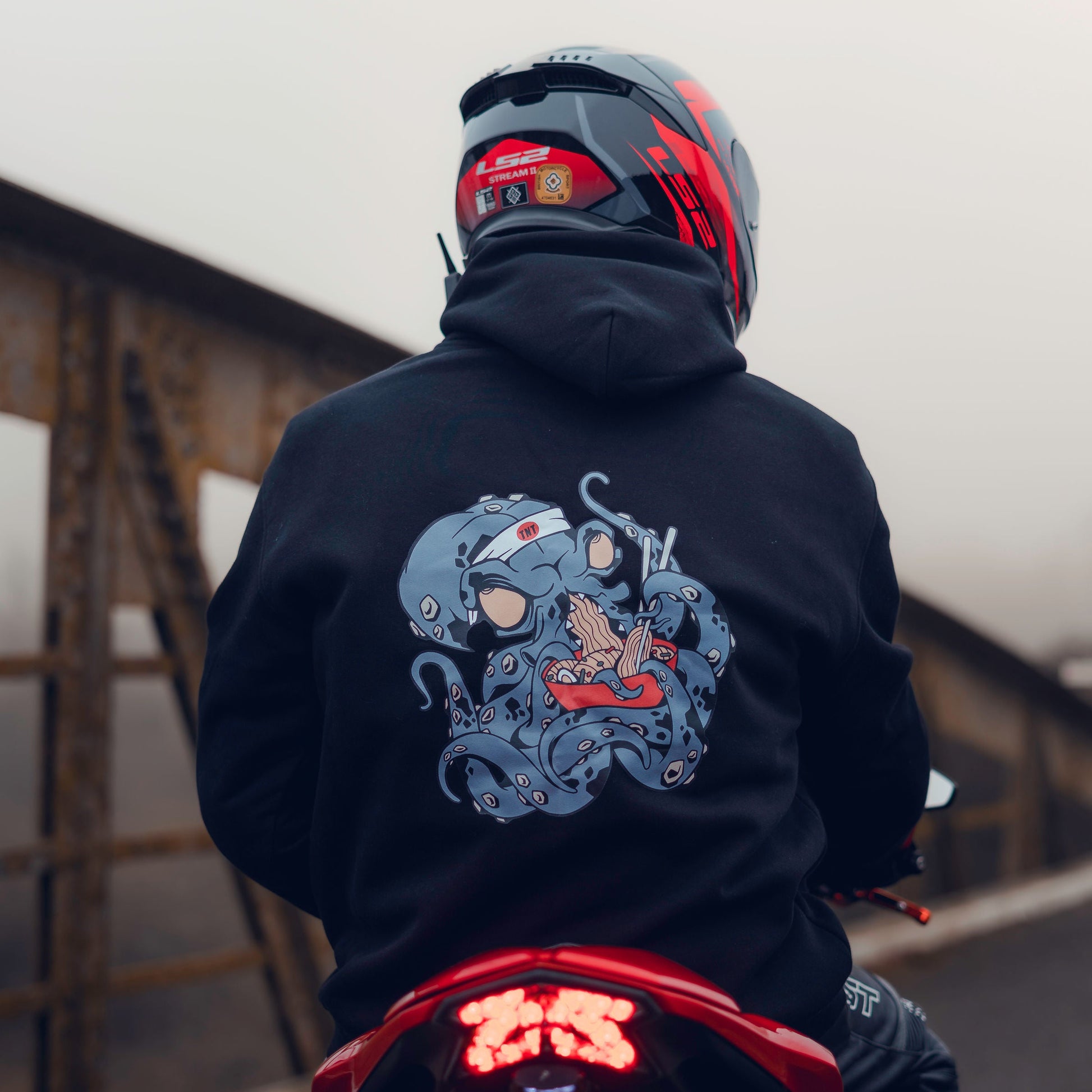 Throttle and Tarmac Black Oversized Octopus Hoodie being shown from the back and being worn on a motorcycle.